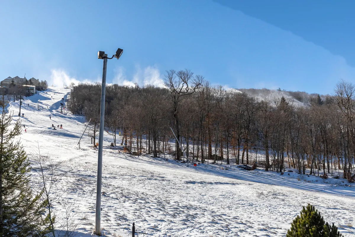 A dynamic winter scene featuring ski slopes, snow-covered landscapes, and skiers in action. Snowmaking machines are visible, highlighting the area’s readiness for winter sports. The image evokes excitement and anticipation for adventure right outside the property.