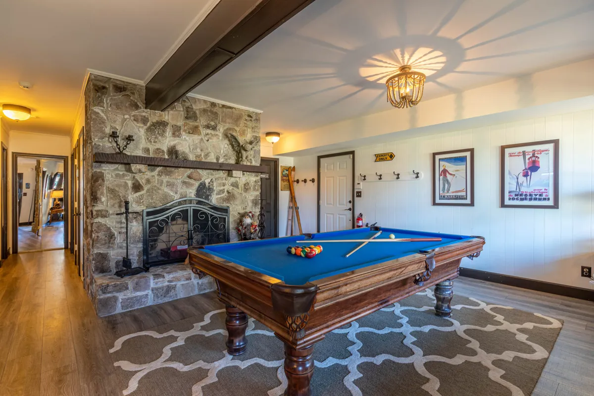 This image features a pool table set in a cozy den with a stone fireplace and decorative wall art. The ambiance is fun and relaxed, evoking the spirit of friendly competition and socializing in a welcoming environment.